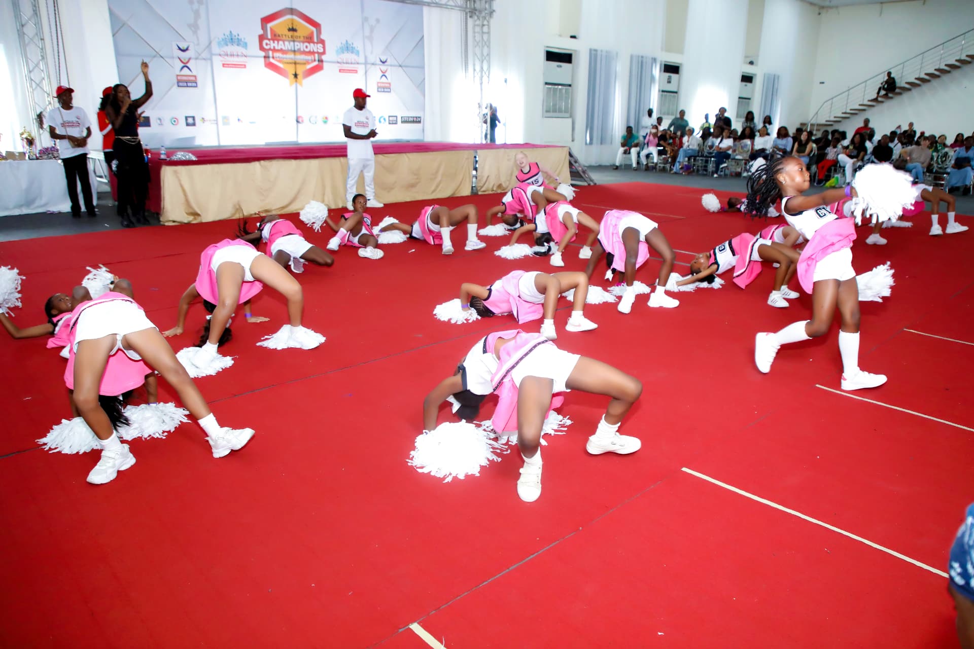 Cheerleaders performing a group routine on the red mat