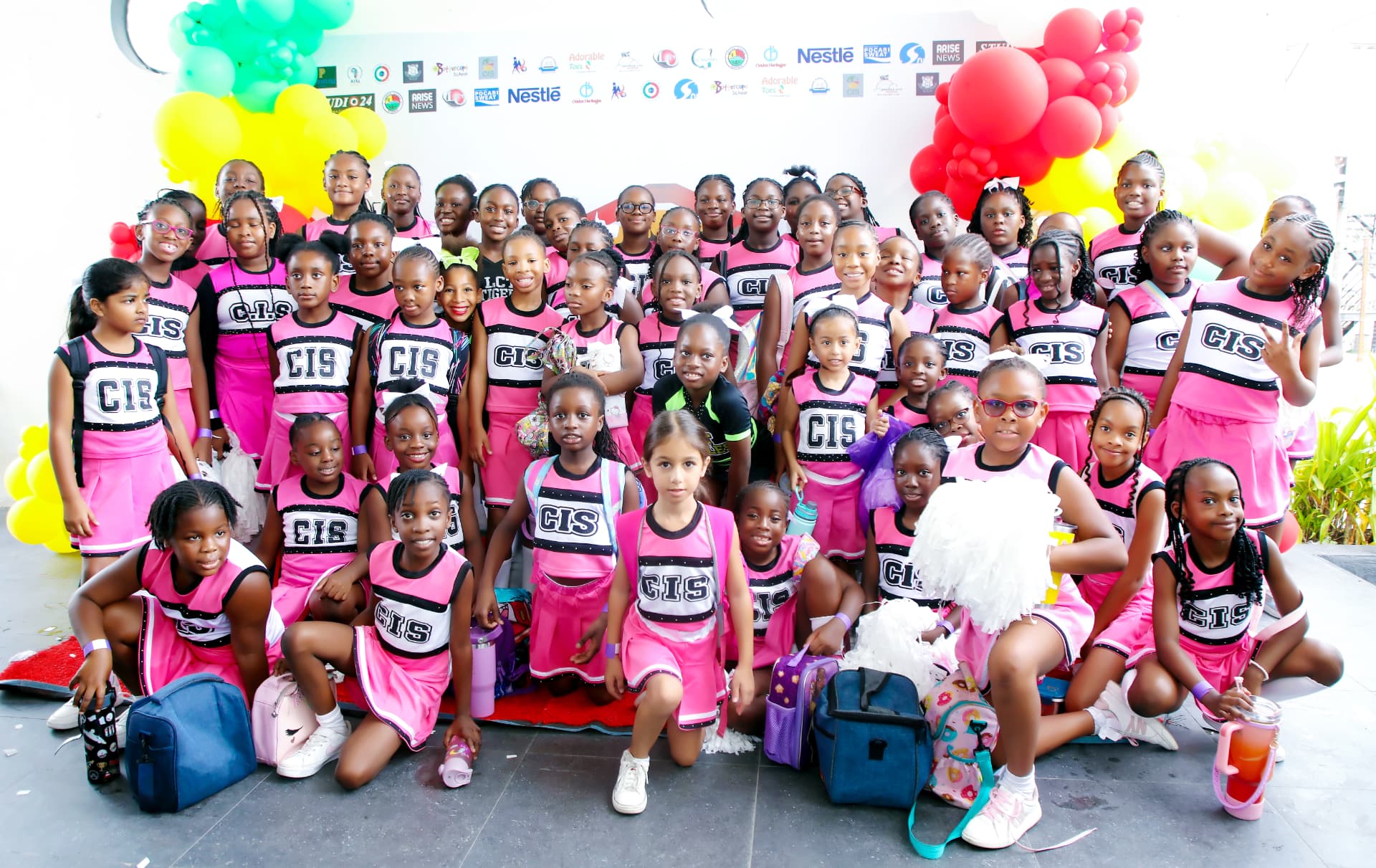 A cheerleading team in pink and black uniforms gathered for a group photograph
